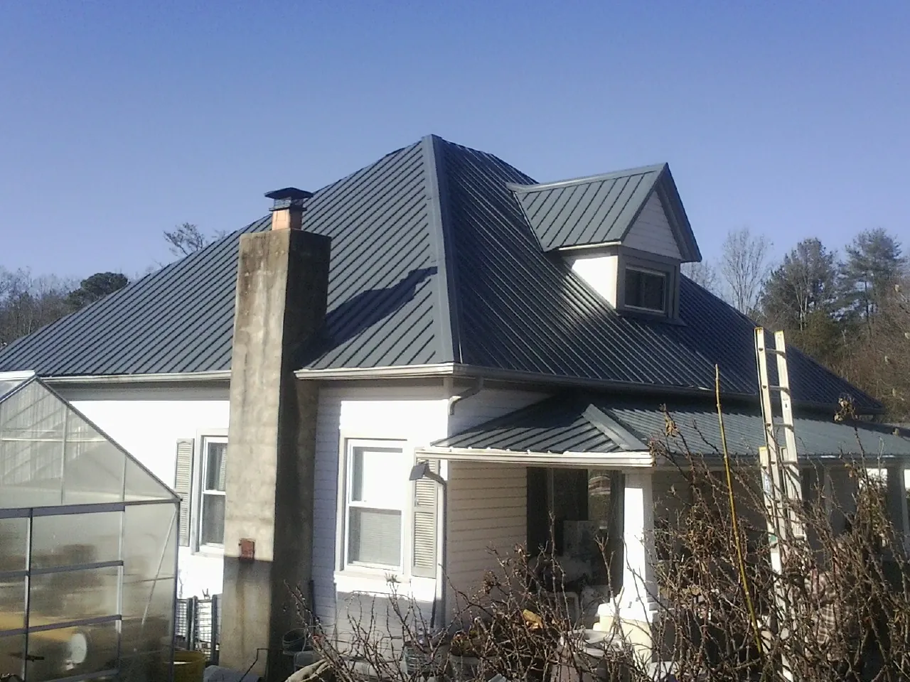 Dark blue standing seam metal roof on a white farmhouse with dormer — Slate & Tile Roof Repair by Roofing Brothers in Wade