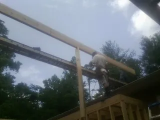 Carpenter setting a ridge beam over a new addition frame — Ice Dam Removal by Roofing Brothers in Wade