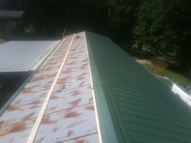 Old rusted panels beside newly installed green metal roofing — Wind Damage Roof Repair by Roofing Brothers in Wade