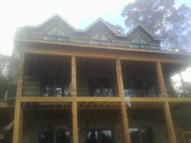 Dormers and porch framing on a large log home under construction — Roof Coating work by our crew in Wade