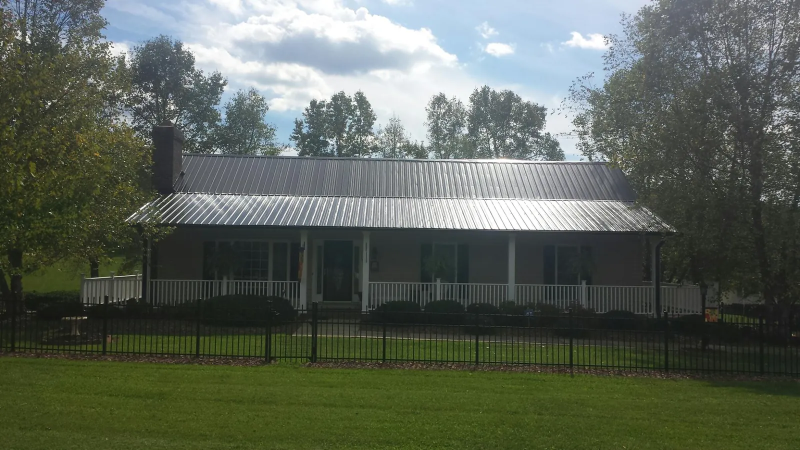 Gray metal roof on a brick ranch with a full width front porch — Gutter Guard Installation work by our crew in Wade