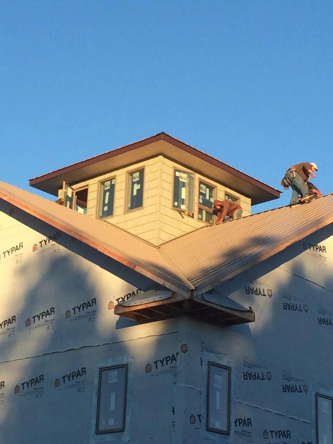 Roofers working around a rooftop cupola on a new metal roof at sunset — Roof Waterproofing in Wade by Roofing Brothers